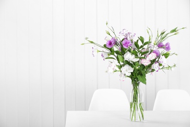 Photo of Glass vase with bouquet of beautiful flowers on table in room. Space for text