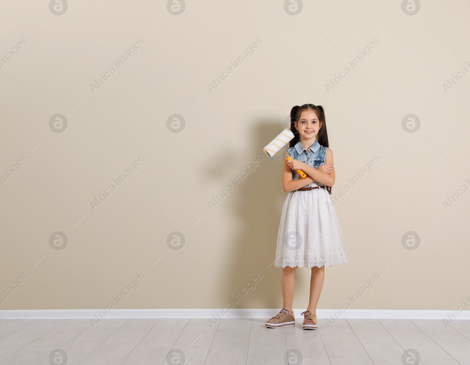 Photo of Child with roller brush near color wall. Space for text