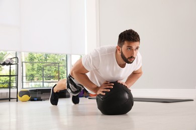 Photo of Athletic man doing push ups with medicine ball in modern gym