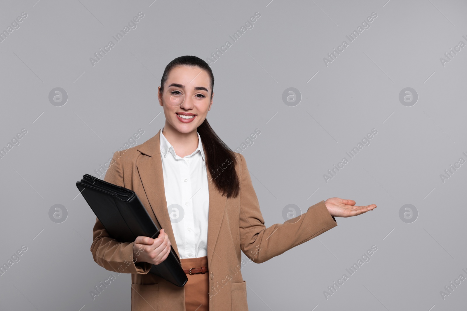 Photo of Happy real estate agent with leather portfolio on grey background. Space for text