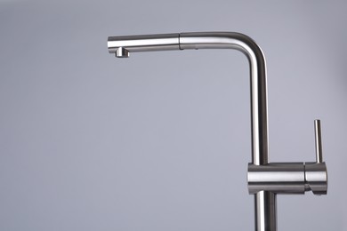 Photo of Modern pull out kitchen faucet on grey background. Space for text