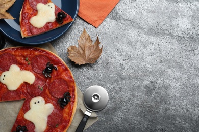 Cute Halloween pizza with ghosts and spiders served on grey table, flat lay. Space for text