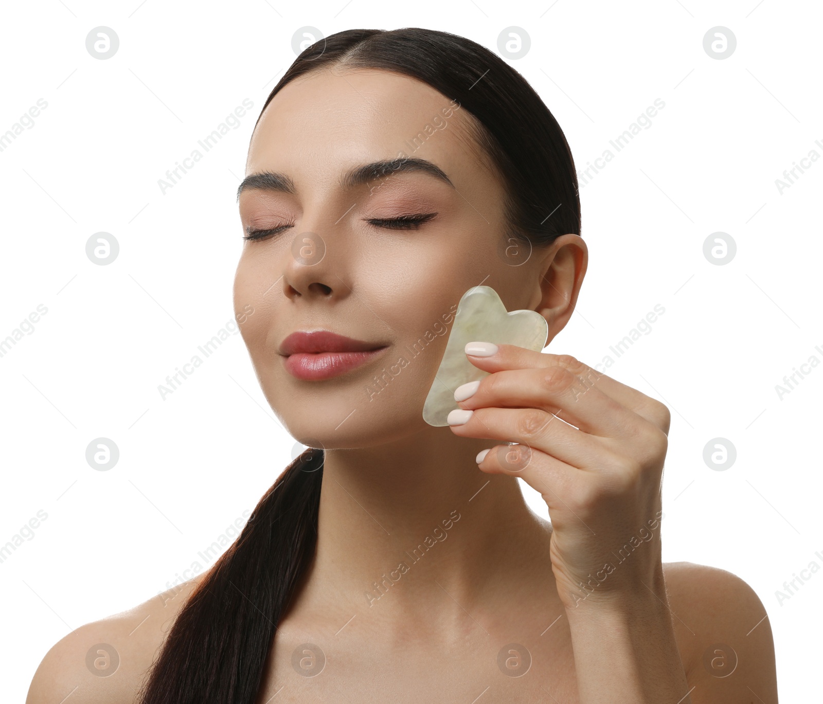 Photo of Beautiful young woman doing facial massage with gua sha tool on white background