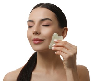 Beautiful young woman doing facial massage with gua sha tool on white background