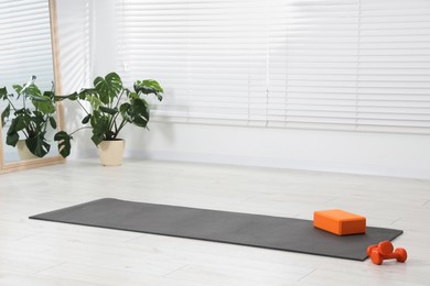 Photo of Exercise mat, yoga block and dumbbells at home. Space for text