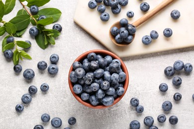 Photo of Tasty fresh blueberries and green leaves on light grey table, flat lay