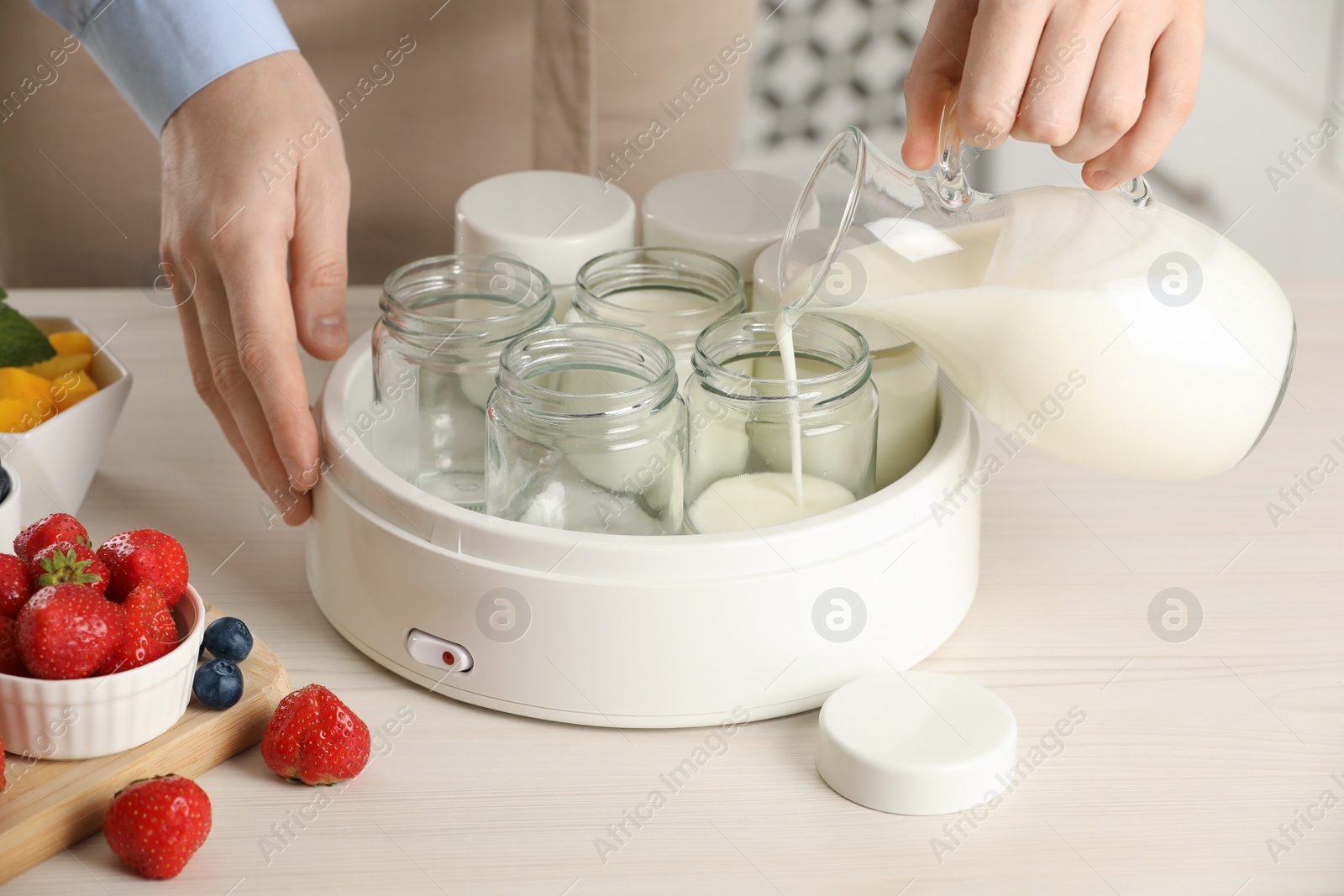 Photo of Woman making tasty yogurt at white wooden table indoors, closeup