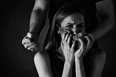 Image of Man abusing scared woman on black background. Domestic violence