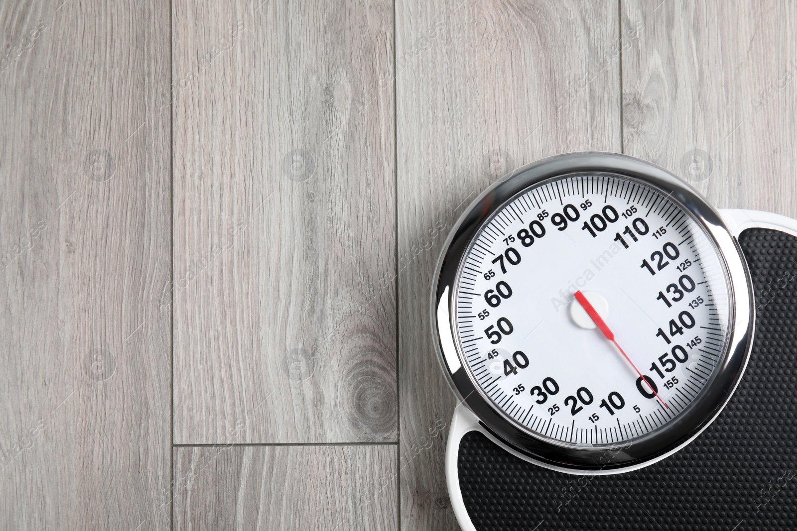 Photo of Modern scales on wooden floor, top view with space for text