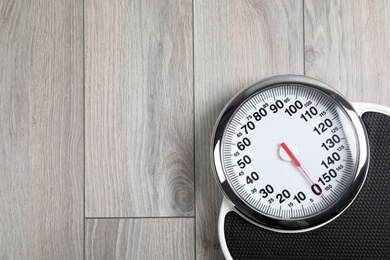 Modern scales on wooden floor, top view with space for text