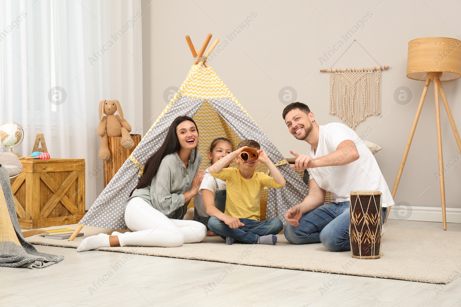Photo of Happy family with treasure map near toy wigwam at home