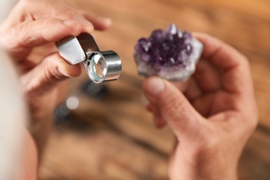 Male jeweler evaluating semi precious gemstone at table in workshop, closeup