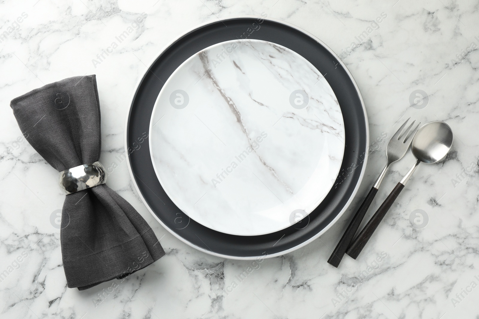 Photo of Stylish setting with cutlery, napkin and plates on white marble table, top view