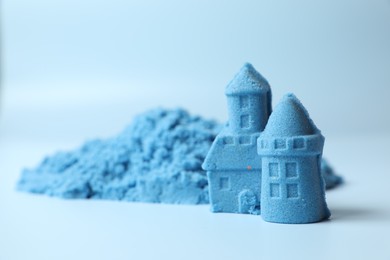 Castle figures made of kinetic sand on light blue background, closeup. Space for text