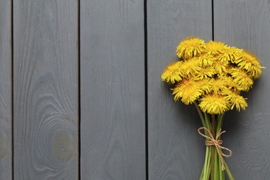Photo of Beautiful dandelion bouquet on grey wooden table, top view. Space for text