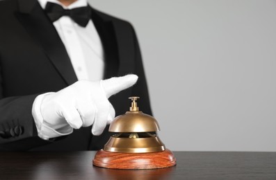 Photo of Butler ringing service bell at table, closeup. Space for text