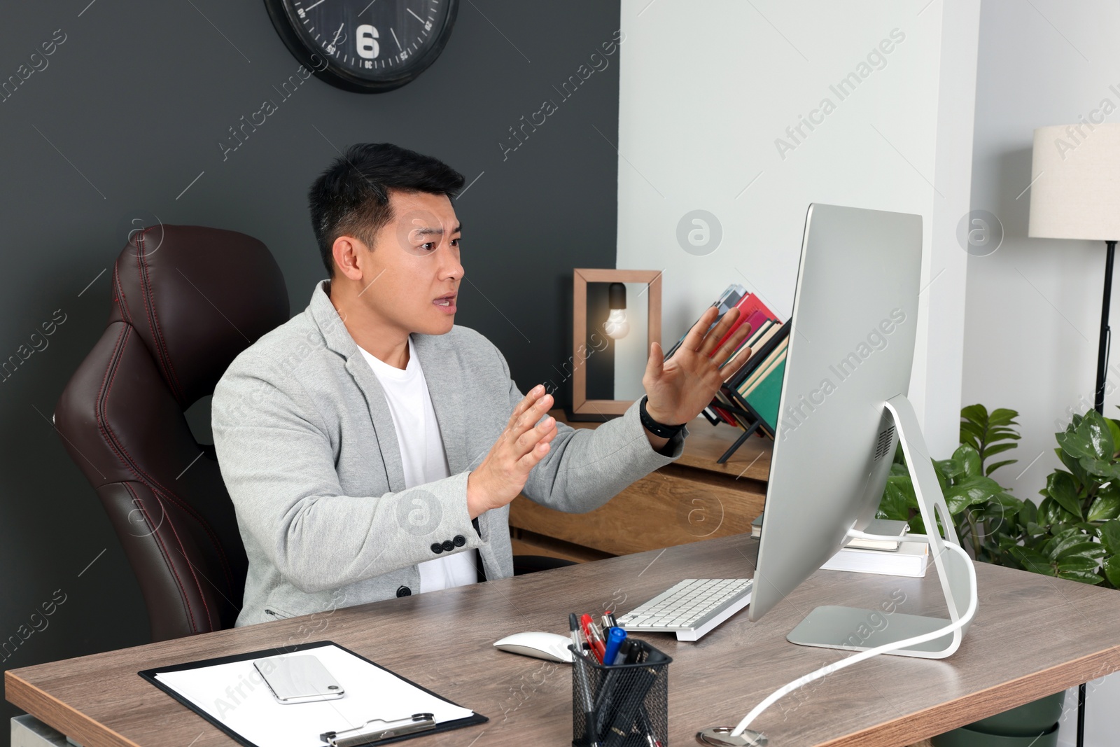 Photo of Emotional boss having online meeting via computer at wooden table in modern office
