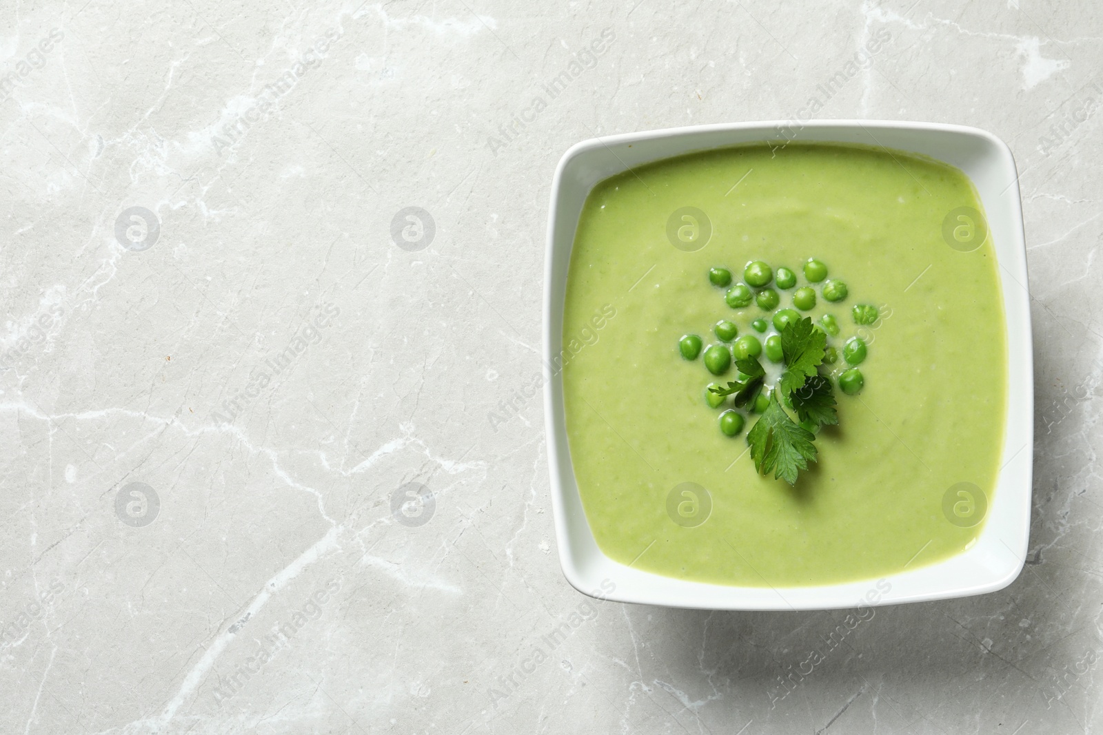 Photo of Fresh vegetable detox soup made of green peas in dish and space for text on table, top view