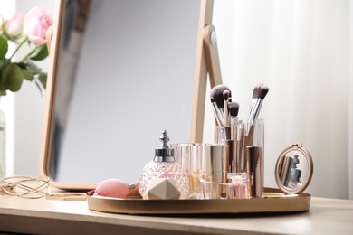 Photo of Different makeup products and accessories on dressing table in room interior