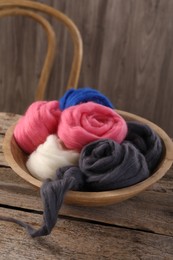 Photo of Colorful felting wool in bowl on wooden table