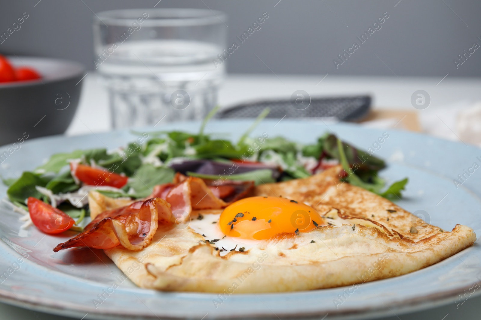 Photo of Delicious crepe with egg on table, closeup. Breton galette