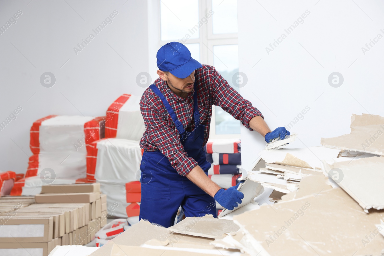 Photo of Construction worker with used drywall in room prepared for renovation