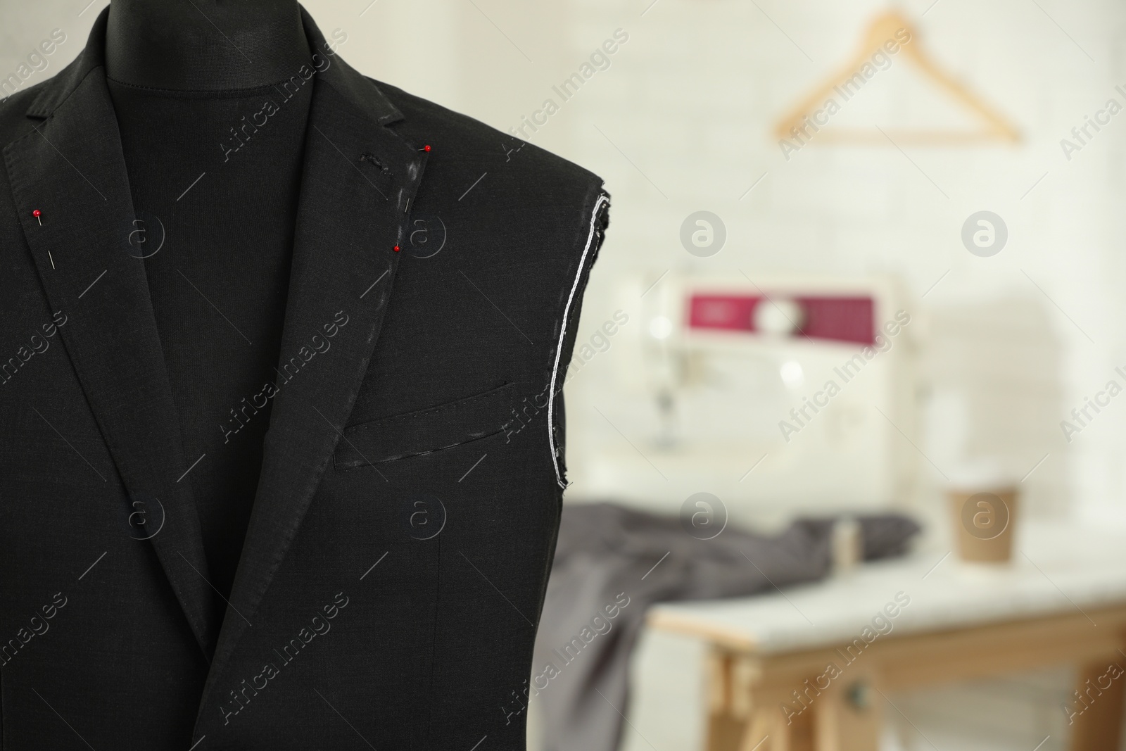 Photo of Mannequin with unfinished jacket in tailor shop, closeup. Space for text