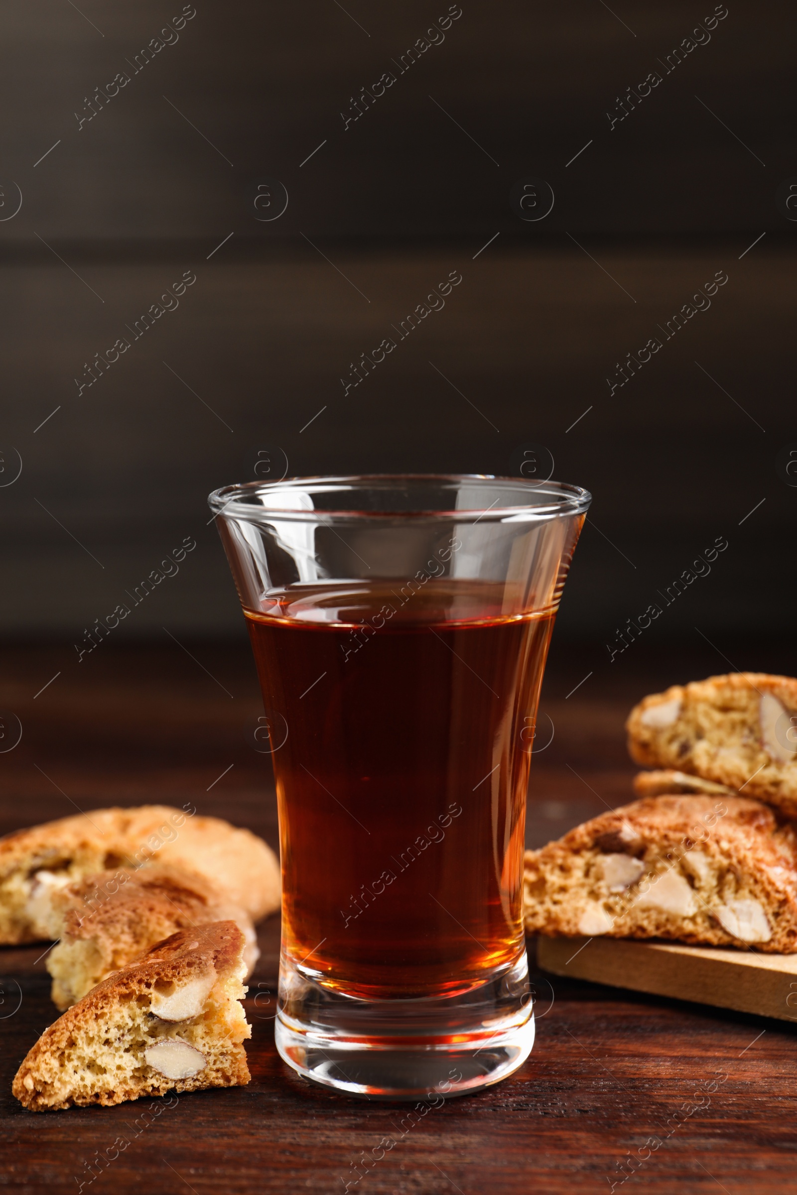 Photo of Tasty cantucci and glass of liqueur on wooden table. Traditional Italian almond biscuits