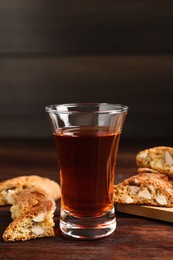 Photo of Tasty cantucci and glass of liqueur on wooden table. Traditional Italian almond biscuits