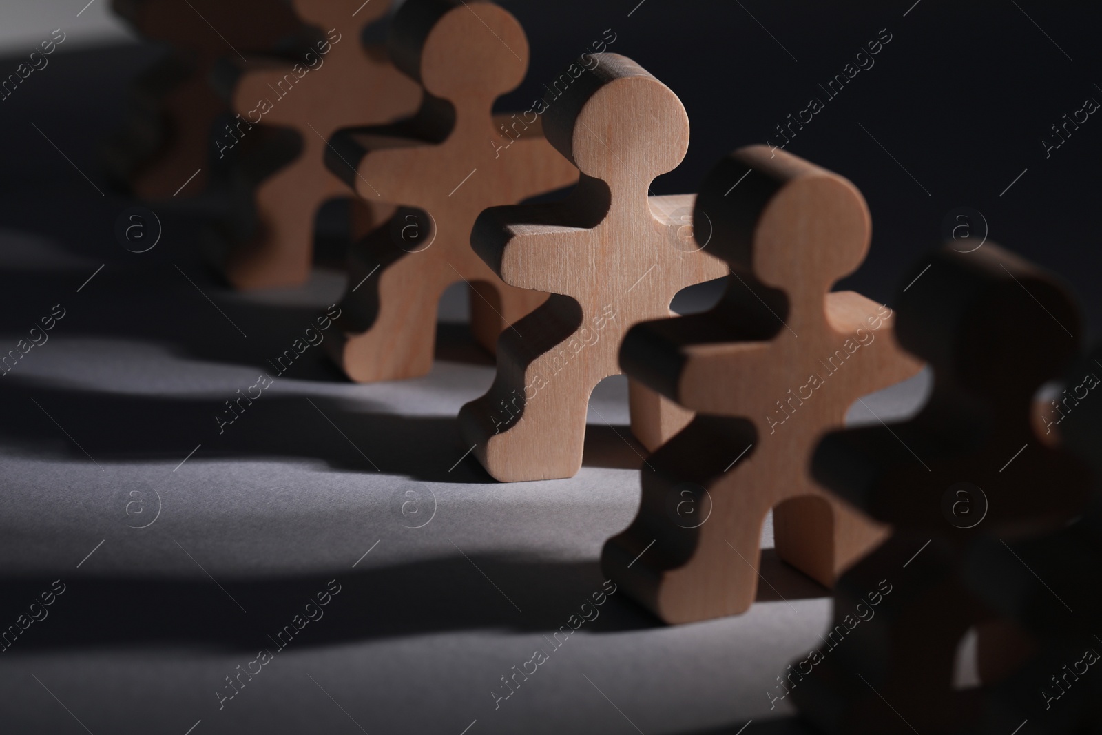 Photo of Recruitment and hiring concept. Human wooden figure in beam of light among others on table, closeup