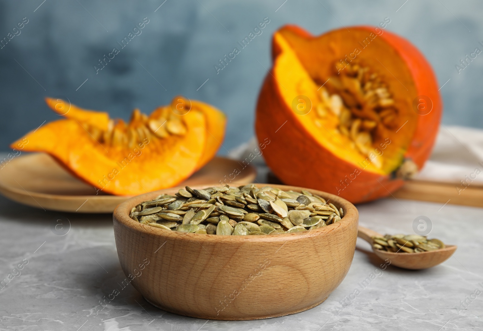 Photo of Bowl of raw pumpkin seeds on light grey marble table