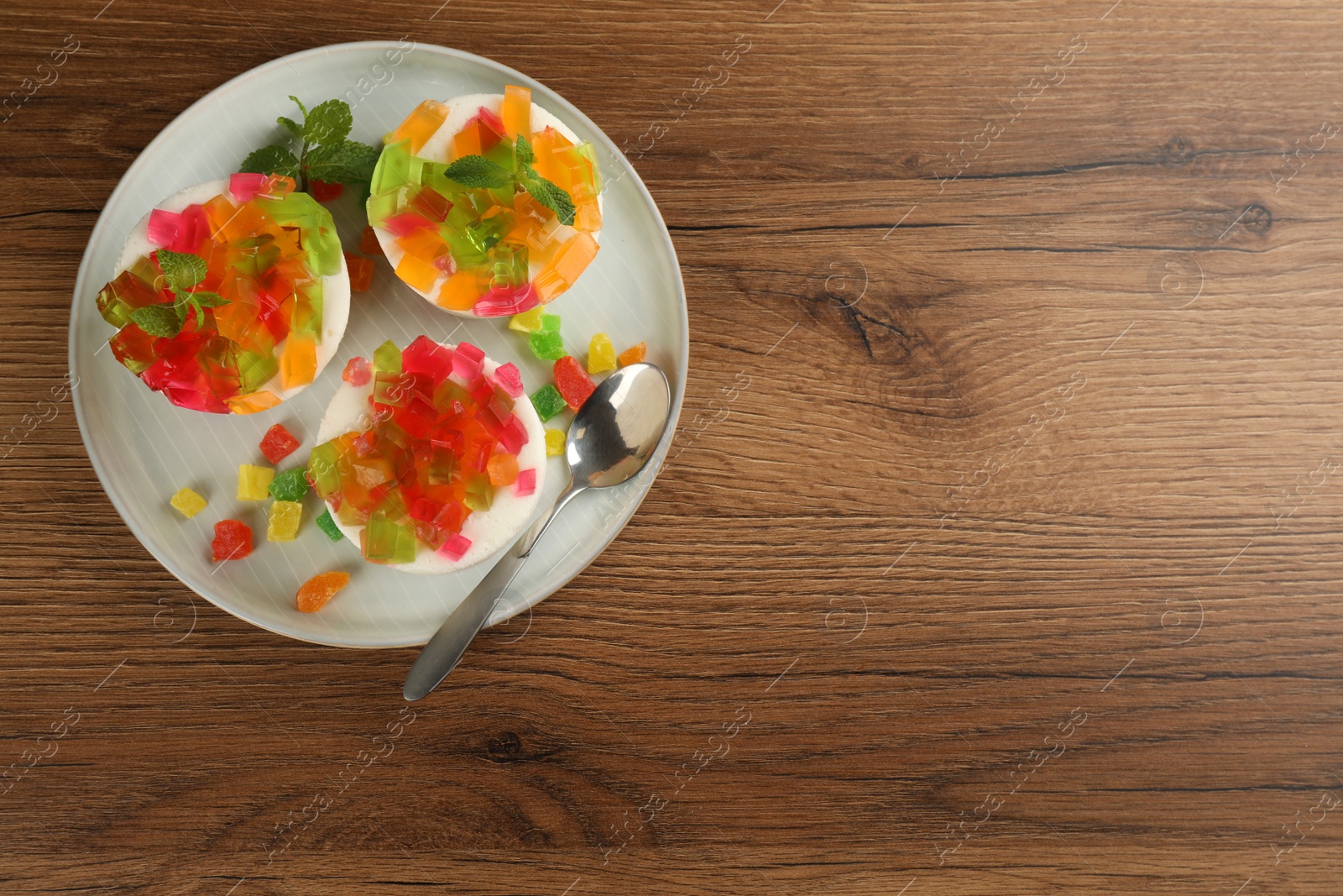 Photo of Delicious broken glass jelly dessert on wooden table, top view. Space for text