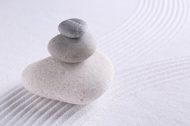 Photo of Zen garden stones on white sand with pattern, space for text