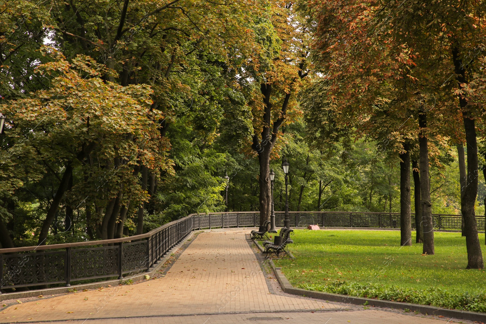 Photo of Quiet park with benches, street lights and pathway