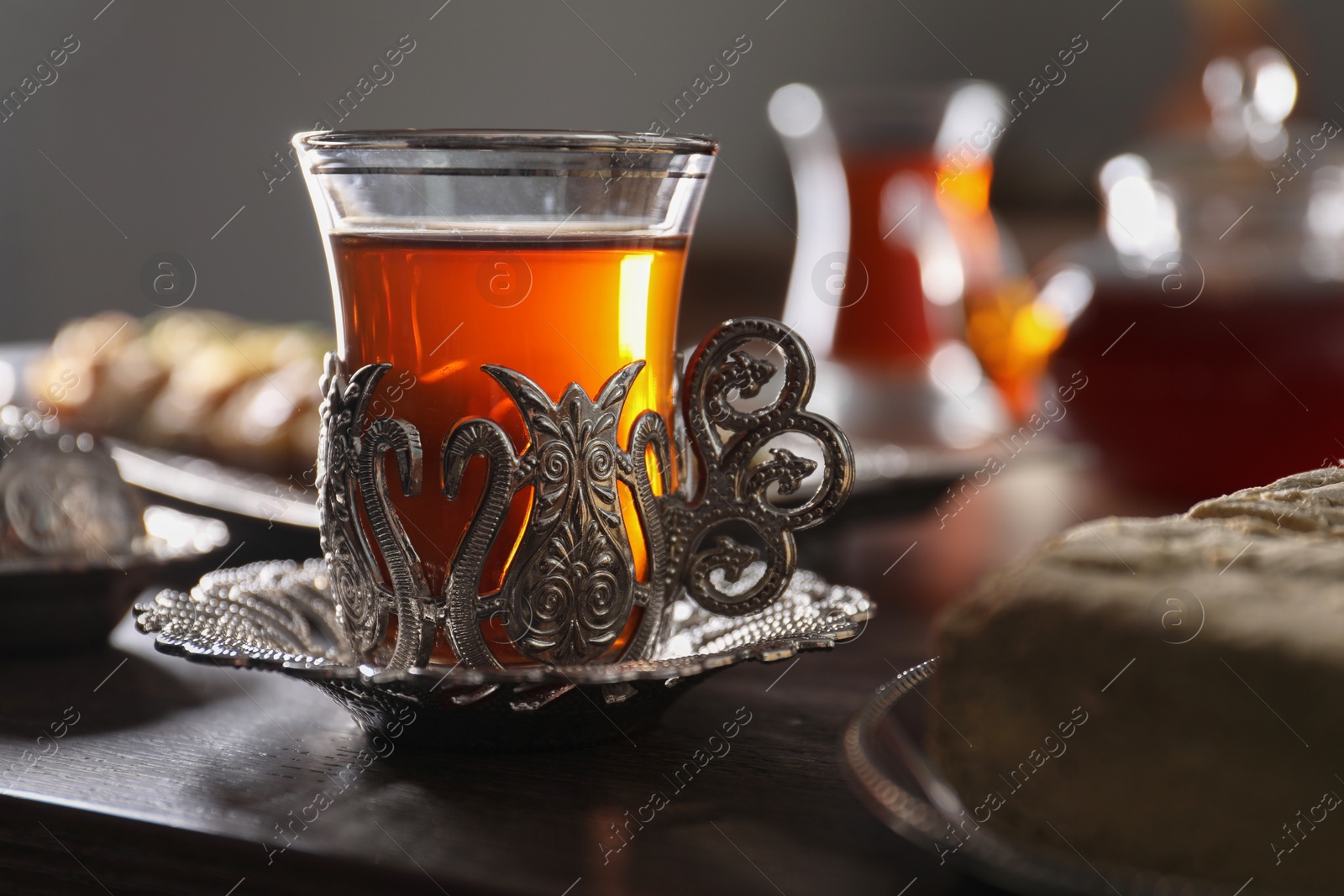 Photo of Glass of traditional Turkish tea in vintage holder on wooden table, closeup