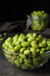 Bowl of delicious edamame beans on grey table against dark background, closeup