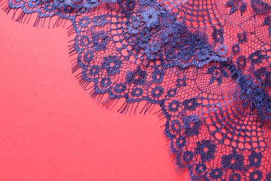 Photo of Blue lace on red background, top view. Space for text