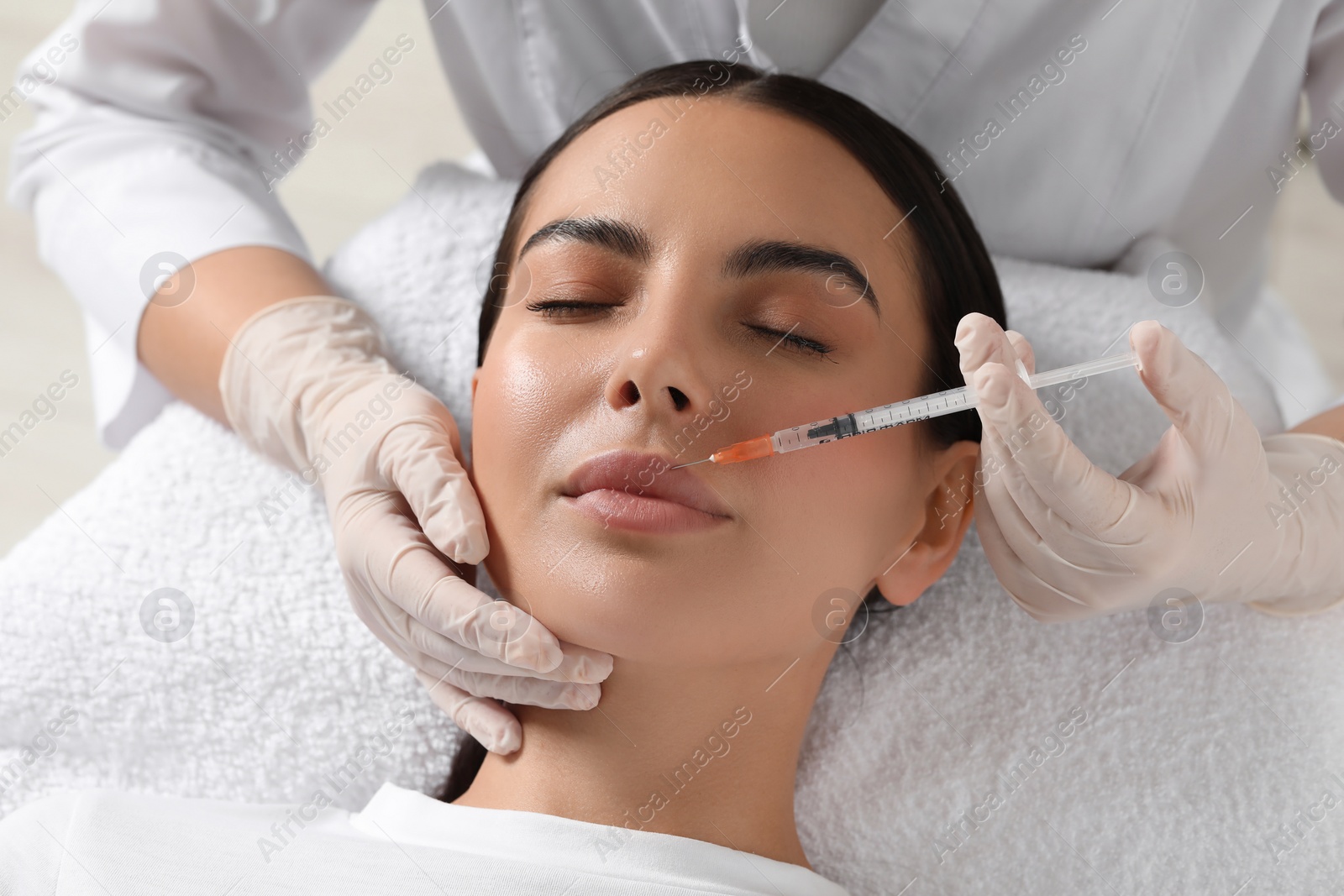 Photo of Doctor giving lips injection to young woman in clinic. Cosmetic surgery