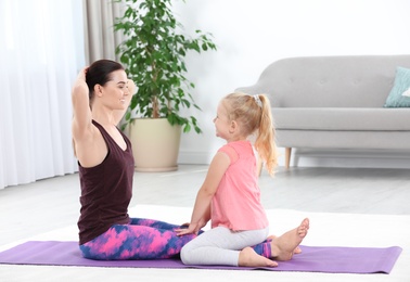 Photo of Sportive woman doing fitness exercises with daughter at home