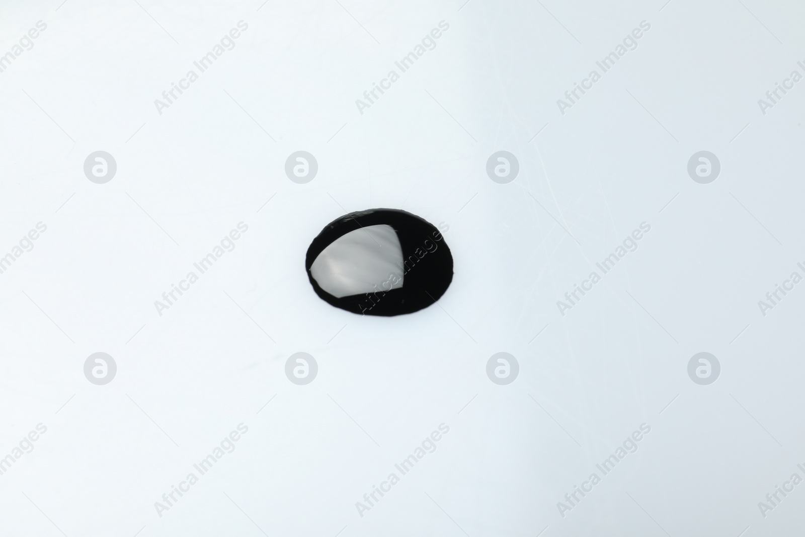 Photo of Black glossy oil blob isolated on white, top view