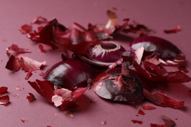 Peels of fresh red onion on dark pink background, closeup