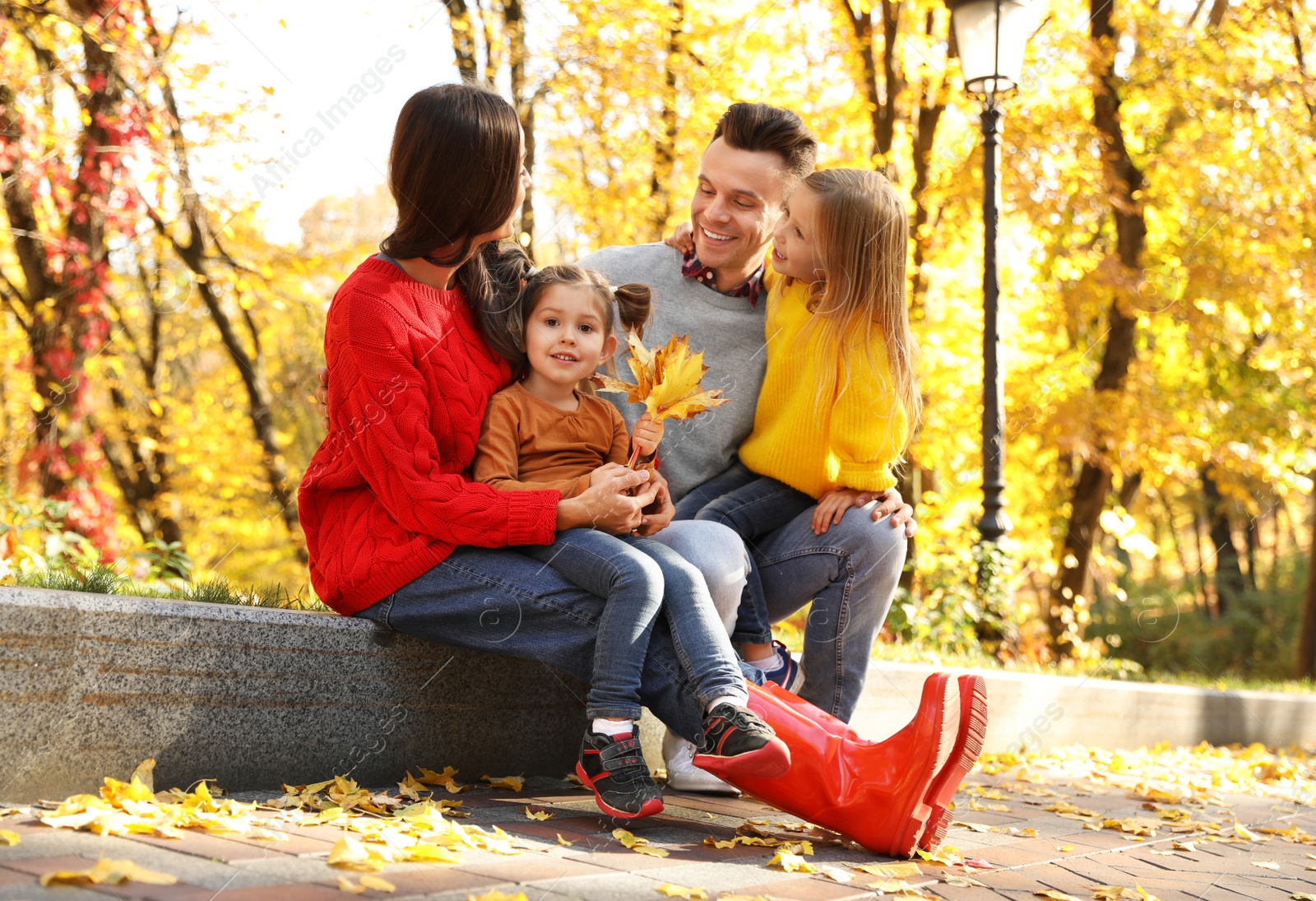 Photo of Happy family with little daughters in park. Autumn walk