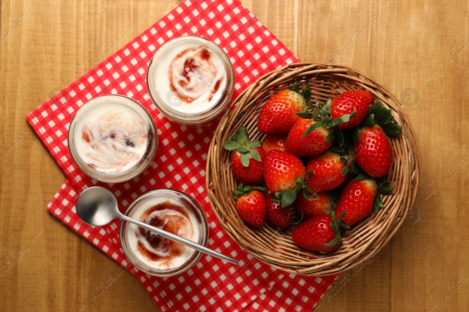 Photo of Tasty yoghurt with jam and strawberries on wooden table, top view