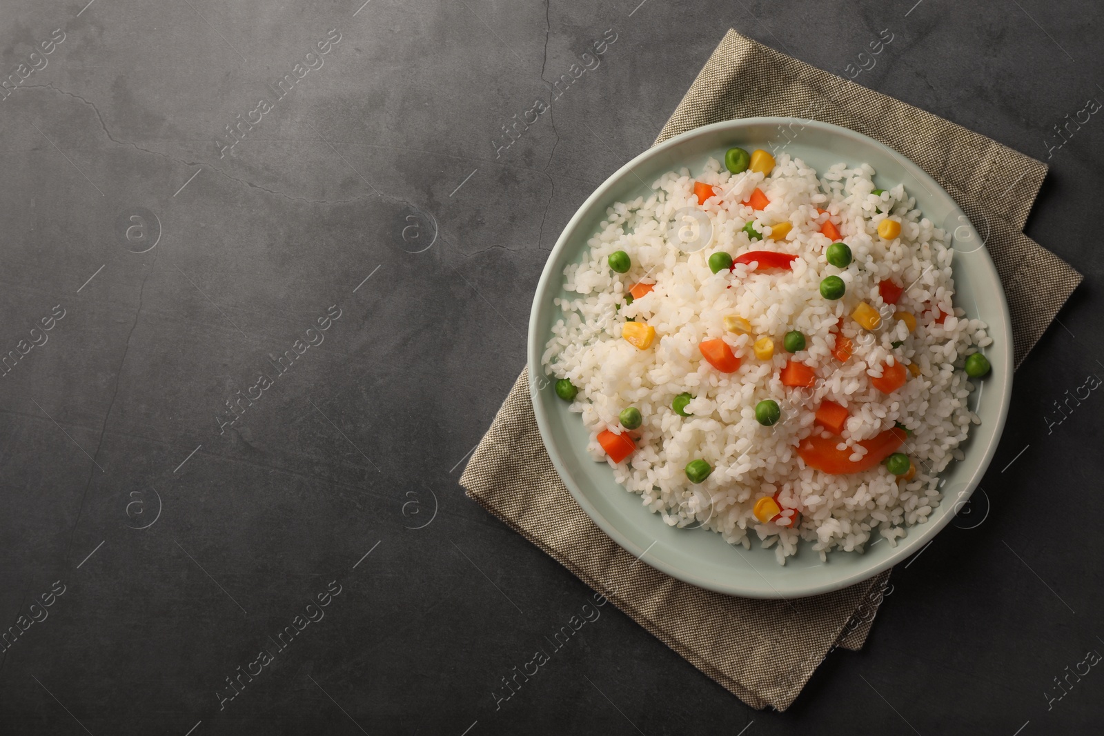 Photo of Delicious rice with vegetables on grey table, top view. Space for text