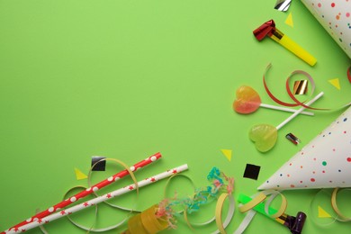 Colorful blowers, streamers and other festive decor on light green background, flat lay. Space for text