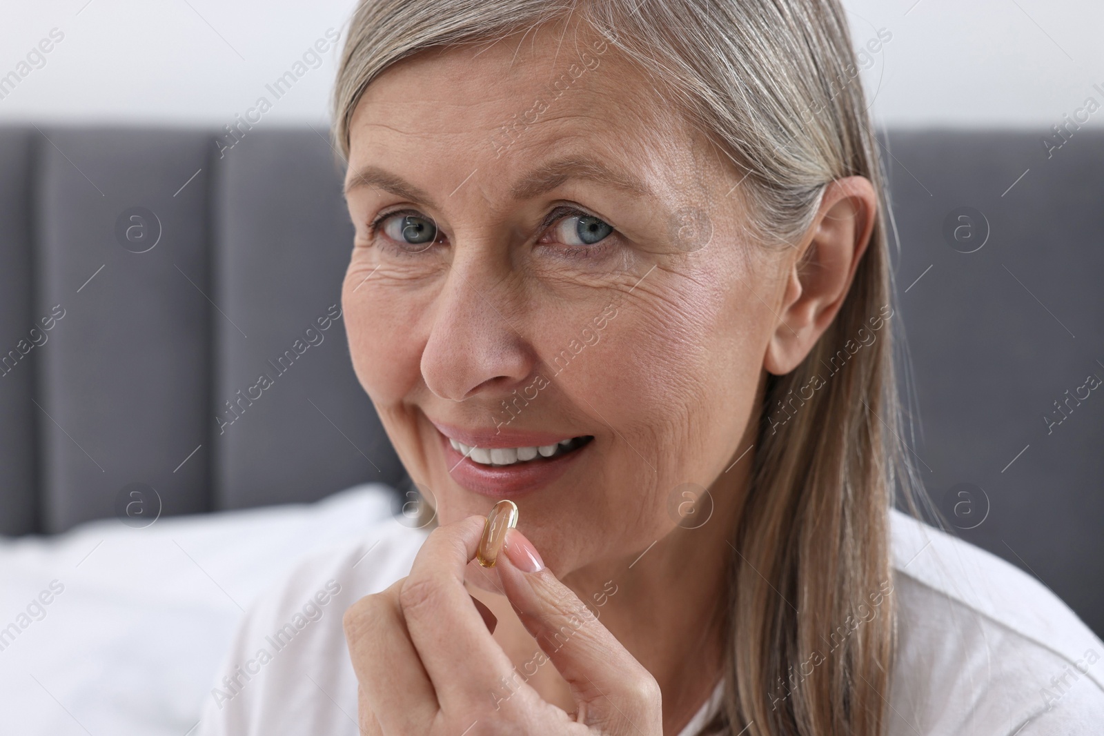 Photo of Beautiful woman taking vitamin pill at home