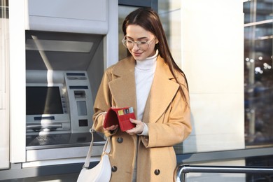 Photo of Happy young woman with credit cards near cash machine outdoors