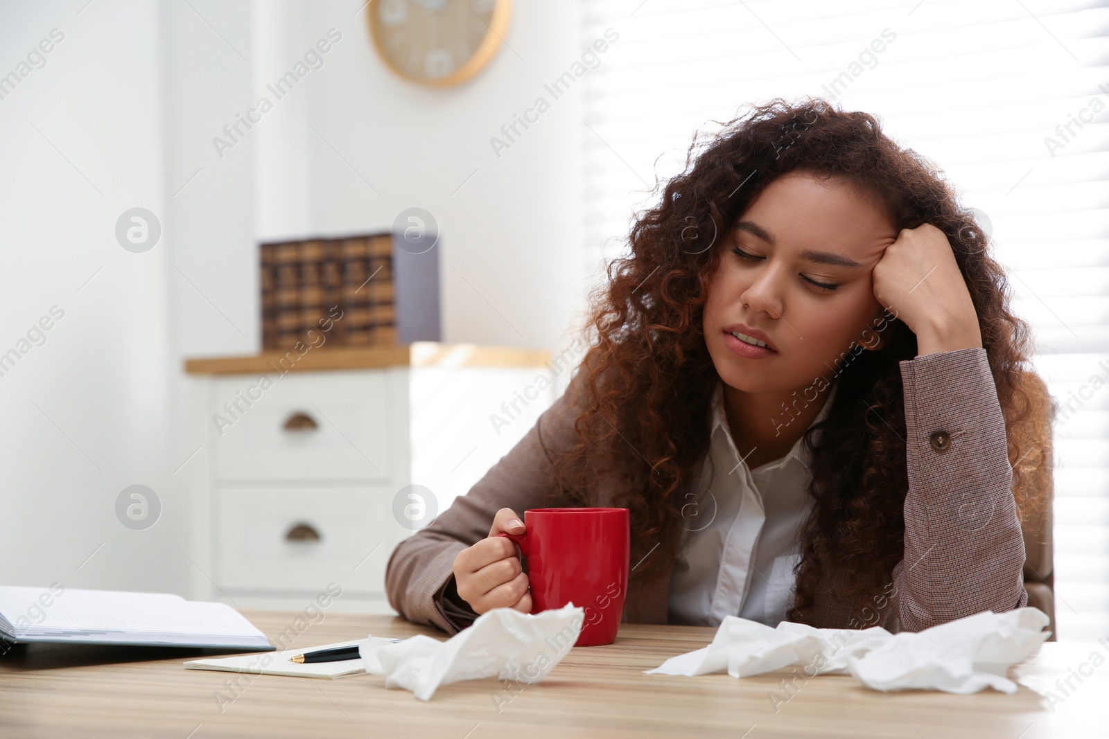 Photo of Sick African-American woman at workplace. Influenza virus