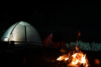 Bonfire near camping tents outdoors at night