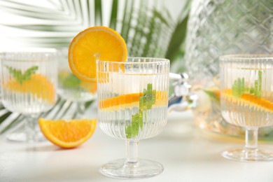 Delicious refreshing drink with orange and mint on white table